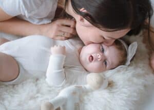 Mom kissing her newborn baby, top view.
