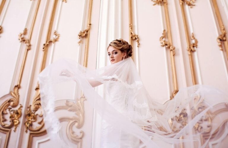 Beauty bride in bridal gown with lace veil indoors